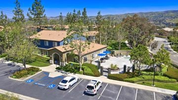 Anaheim Hills apartment for rent - A parking lot with a building and a pool in the background.