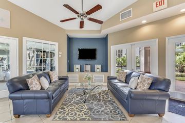 Orlando apartment for rent - A living room with a black leather couch and a ceiling fan.