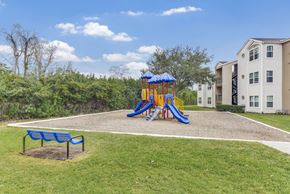 Orlando apartment for rent - A playground with a blue slide and a bench in the foreground.