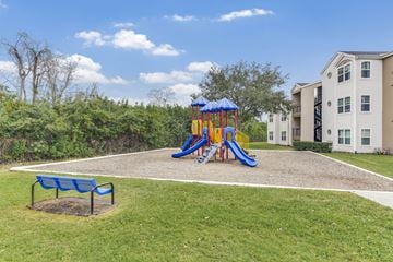 Orlando apartment for rent - A playground with a blue slide and a bench in the foreground.