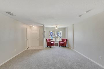 Orlando apartment for rent - A living room with a grey carpet and two red chairs.