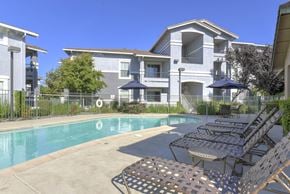 Dixon apartment for rent - A swimming pool surrounded by chairs and umbrellas in front of a building.at Lincoln Creek Apartments, Dixon, CA 95620