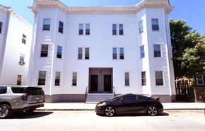 Roxbury apartment for rent - A black car is parked in front of a white building.