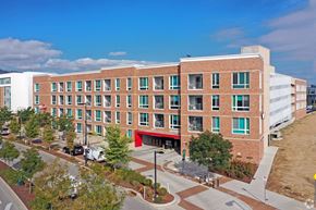 Boulder apartment for rent - A large red brick building with a red awning sits in front of a parking lot at Depot Square in Boulder, CO