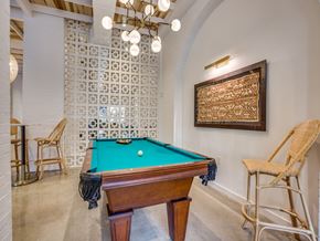 Dallas apartment for rent - A pool table with a green cloth and a wooden frame is in the center of the room.