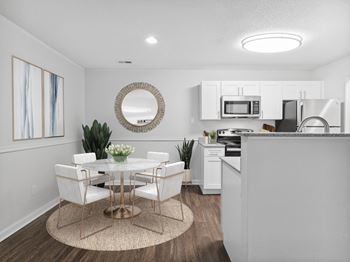 A dining area with a table and chairs and a kitchen in the background
