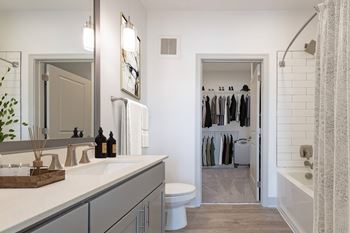 A bathroom with a sink and a toilet and a walk in closet