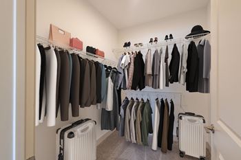 A closet with a rack of clothes and a suitcase