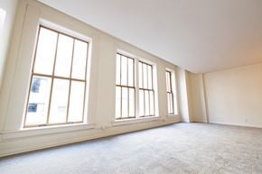 Indianapolis apartment for rent - an empty living room with three large windows at 26 West, Managed by Buckingham Urban Living, Indianapolis