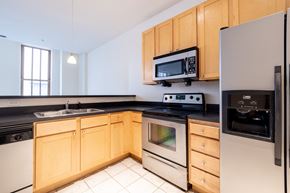 Indianapolis apartment for rent - a kitchen with wooden cabinets and stainless steel appliances at 26 West, Managed by Buckingham Urban Living, Indianapolis