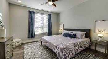 A bedroom with a bed, nightstand, and a ceiling fan.