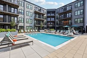 Cincinnati apartment for rent - A swimming pool surrounded by lounge chairs and apartment buildings.