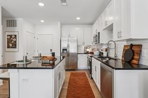 Cincinnati apartment for rent - Sleek kitchen at Contrast OTR apartments in Cincinnati, OH with a large center island, modern lighting, and white shaker cabinets.