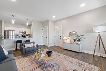 Foley apartment for rent - A modern living room with a grey sofa, a round table with a plant on it, and a white cabinet with a lamp on top.