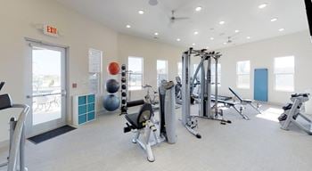 A gym with a variety of equipment including a treadmill, weights, and a squat rack.