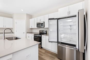 A modern kitchen with a refrigerator, sink, and cabinets.
