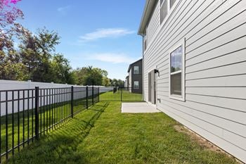 A white house with a black fence and green grass.