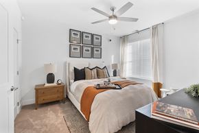 Indianapolis apartment for rent - A bedroom with a large bed, a ceiling fan, and a nightstand with a lamp.