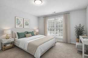 Raleigh apartment for rent - A bedroom with a large bed, a desk, and a window with blinds.