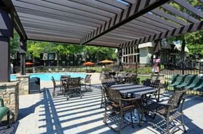 Marietta townhouse for rent - a patio with tables and chairs next to a swimming pool at Elea Apartments in Marietta, GA