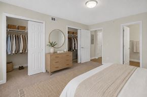 Nashville apartment for rent - A bedroom with a large bed and a closet with clothes hanging.