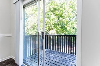 A balcony with glass doors and a view of trees