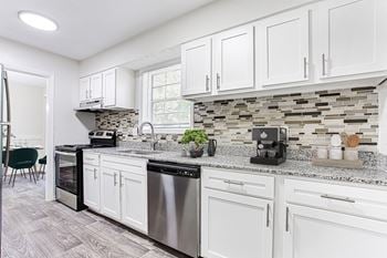An open kitchen with white cabinets and granite counter tops