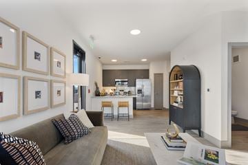 West Lafayette apartment for rent - A modern living room with a grey couch and a kitchen in the background.