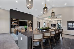West Lafayette apartment for rent - Community bar and lounge area with oversized island seating, pendant lighting, built-in shelving, and modern finishes at Montage apartment community