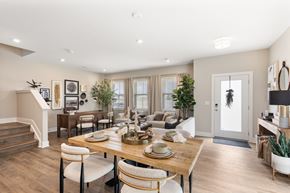 Lewis Center apartment for rent - Bright open-concept dining and living space at Mural Lewis Center featuring wood-style flooring, large windows, modern dining table, neutral decor, and seamless flow into the kitchen and living room
