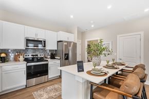 Lewis Center apartment for rent - Open-concept apartment kitchen at Mural Lewis Center featuring large island with seating, white cabinetry, stainless steel appliances, subway tile backsplash, and wood-style flooring
