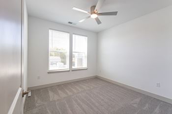 An empty room with a large window and a ceiling lamp