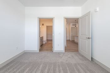 An empty living room with white walls and a door to a bathroom