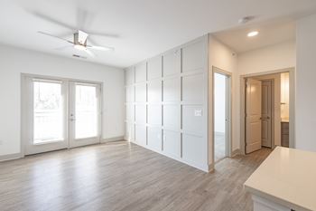 An empty living room with white walls and a ceiling fan