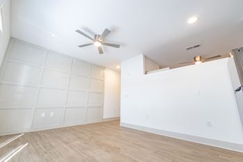 A living room with white walls and a ceiling fan