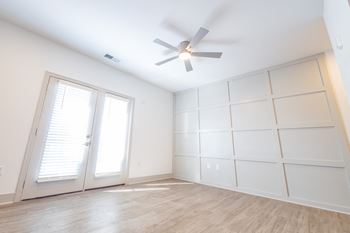 A large white room with two windows and a ceiling fan