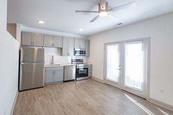 An empty kitchen with stainless steel appliances and a ceiling fan