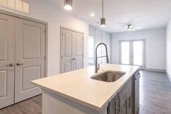 A kitchen with white cabinets and a white counter top and a sink
