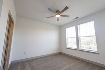 An empty living room with a ceiling fan and a window