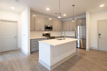 A kitchen with an island and a stainless steel refrigerator
