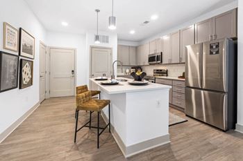 A kitchen with a large island and a stainless steel refrigerator