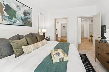 A bedroom with a large bed and a painting on the wall