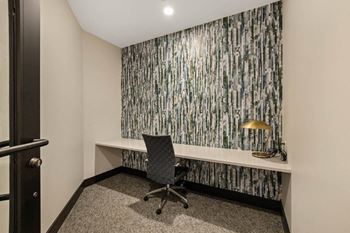 A desk with a chair in a room with a window and a wall mural