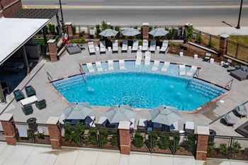 A pool is shown at a hotel with chairs and umbrellas