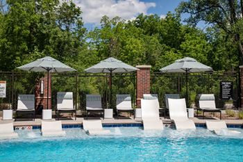 A swimming pool with chairs and umbrellas next to a resort pool