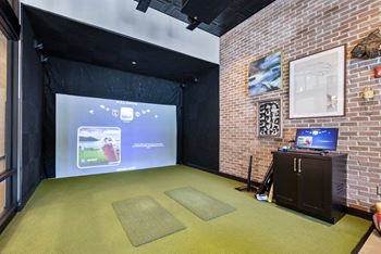 A room with a screen and a projector on a brick wall
