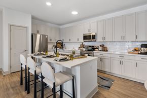 Carmel apartment for rent - Kitchen with sleek light-wood cabinetry, white countertops, a stainless steel under-mount sink with a modern gooseneck faucet, and contemporary built-in appliances.
