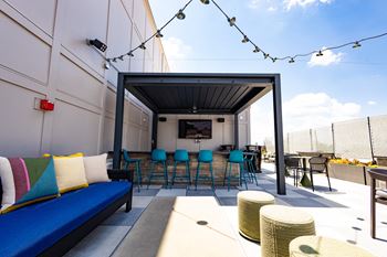 A patio with a couch and chairs and a tv on the wall