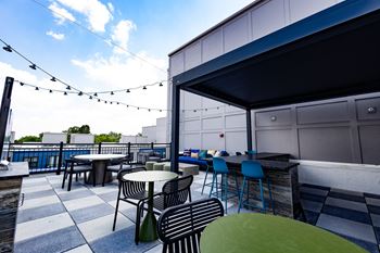 A rooftop patio with tables and chairs and a bar