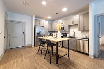 A kitchen with stainless steel appliances and a large island with stools